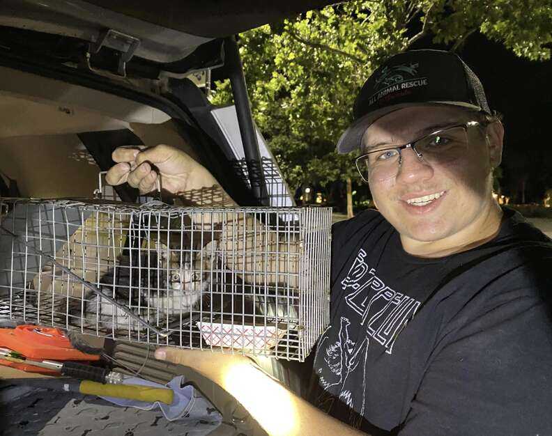 man holding cage with kitten inside